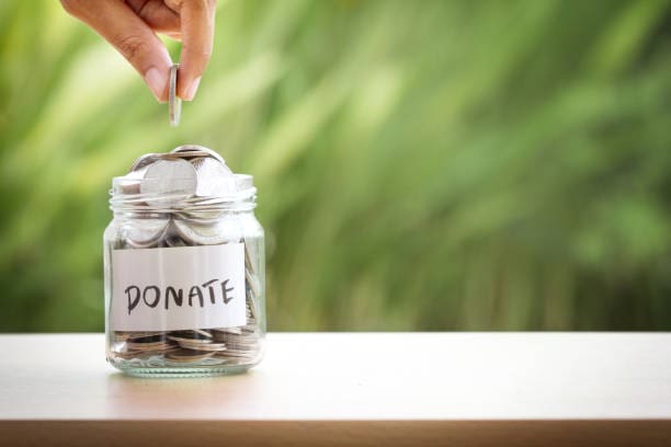 A person putting money in a jar labeled " donate ".